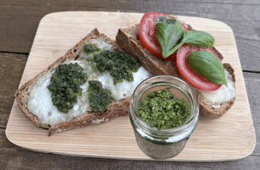 Jar of pesto; mozarella and pesto on one toast and tomato slices and basil on second toast
