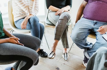 Personen sitzen in einem Kreis während einer Gruppentherapiesitzung.