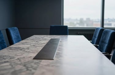 Quiet environmental shot of a modern European boardroom with polished marble table and deep blue velvet chairs, soft overcast daylight, 35mm lens