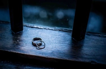 Wedding rings on a dark rustic wooden surface.