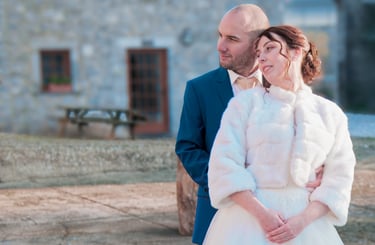 Une mariée vêtue d'un manteau de fourrure blanche et un marié en costume bleu posent