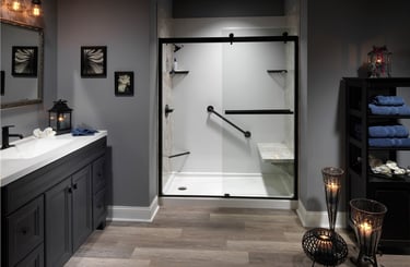 Elegant walk-in shower featuring glass doors with matte black trim, a built-in bench, and safety grab bars, surrounded by a m