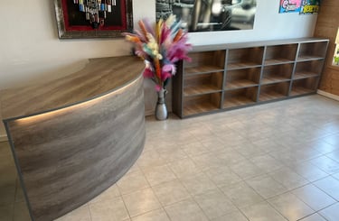 Modern wood reception desk and matching display shelving unit in a barber shop interior.