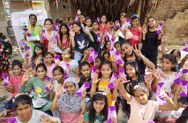 About thirty girls holding up their palms with red dots on.