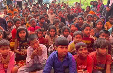 Group of around sixty children sitting on the ground