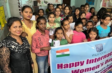 Group of twenty girls, some holding up an International Women's Day banner