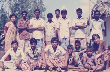 Kayoko standing on the left of 14 Kalamkari artists. some standing and some sitting.