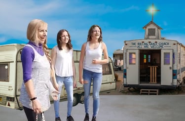 A mobile community center and the Rolling Grace Church trailer with people gathered outside.