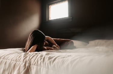 Mother laying beside newborn with sunlight through window, in-home session Duluth MN