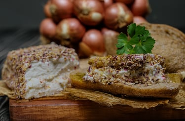 Herbed goat cheese spread on crusty bread with fresh shallots on a rustic wooden board.