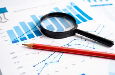 a red pencil and a magnifier on a desk identifying for profits