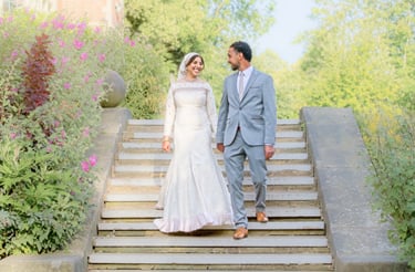 bride and groom walking down step in Stanley home garden, light and airy photo surrounded by flowers 