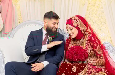 candid photo of asian bride and groom both laughing, groom in dark blue western suit, bride in traditional red dress