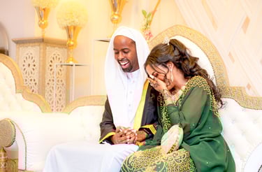 Somalian bride & groom, sitting holding hands laughing and smiling, cream blurred background 