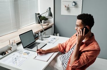 a man on a phone call  sitting at a desk 