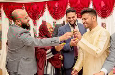 candid photo during Bengali wedding ceremony of groom's family feeding groom, all happy and laughing 