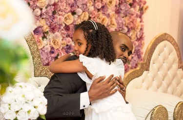 flower girl hugging groom, floral background,, blurry floral in foreground 