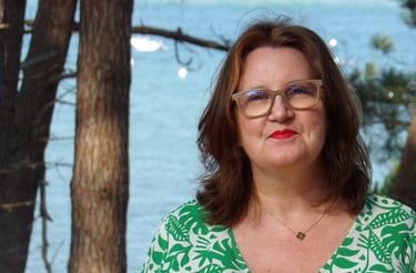 Portrait de la sophrologue en extérieur, devant un paysage de mer et de pins, illustrant le contact.