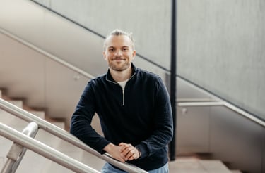 a man in a black jacket and jeans standing on a stair case