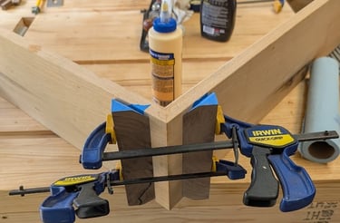 in progress waterfall table, clamped up in workshop  with woodglue and workbench in background