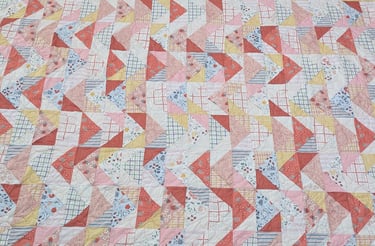 A colorful floral flying geese pattern quilted with a meandering pantograph of daisies