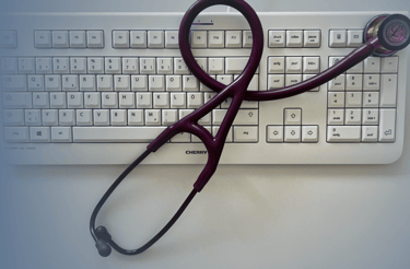 Symbolbild mit weißer Computer-Tastatur und Stethoskop – Kontaktaufnahme mit der Hausarztpraxis