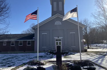 gray country church with flags in the foreground