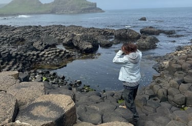 a person standing on a rock formation in the ocean, Ireland, Giant Causeway