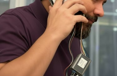PnC engineer on the phone with a client, using a disassembled phone with a debugger hanging