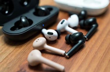 Various wireless Bluetooth earbuds and charging cases displayed on a wooden table for comparison.