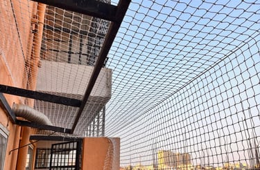 A close-up of hands installing protective pigeon nets on a Bangalore apartment balcony