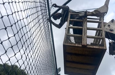 A technician carefully installing a sturdy sports net on a sunny Chennai sports field.