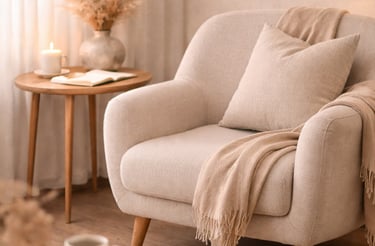 Cozy living room corner with a beige armchair, pampas grass decor, and warm candlelight.