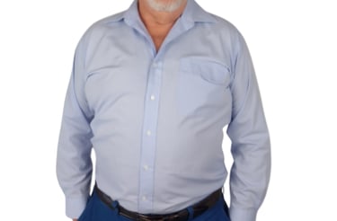 3/4 shot of David-Graham Parker dressed in dark trousers and light blue, long sleeve business shirt.