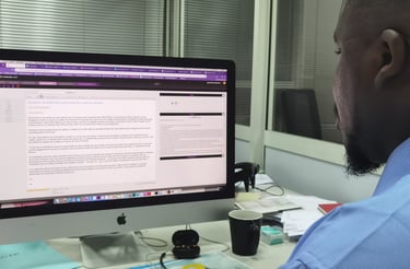 a man sitting at a desk with a computer monitor and a laptop