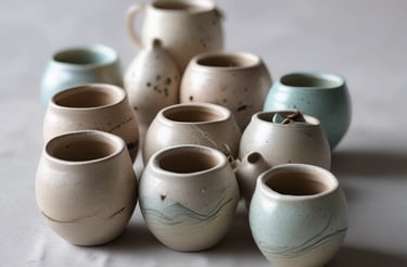 A rustic shelf displays handcrafted pottery including a jug with a cow head handle, a pitcher with a llama face, and a teapot shaped like a chicken.