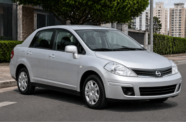 Nissan Tiida Sedan prata estacionado em rua de ambiente urbano durante o dia
