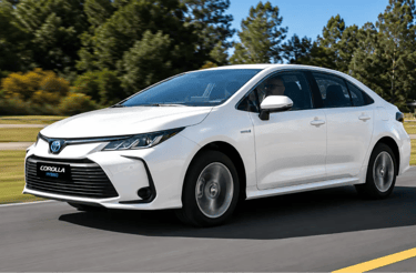 Toyota Corolla Hybrid branco em movimento por uma rodovia cercada por árvores