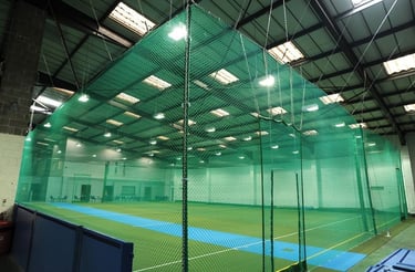 A close-up of a securely installed cricket net against a clear Bengaluru sky.