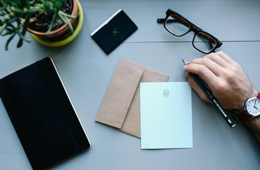 A person's hand holding a pen and writing on a notepad