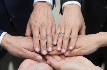 A warm, inviting photo of diverse hands joining together in collaboration outdoors.