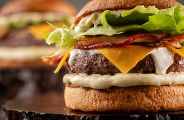 A close-up of a gourmet hamburger featuring a juicy beef patty topped with melted cheese and bacon
