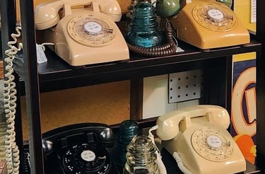 a shelf with a bunch of old fashioned telephone phones