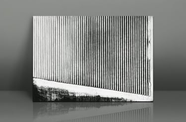 Black and white abstract art print with vertical corrugated lines leaning against a grey wall.