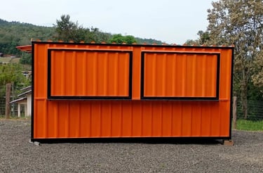 A portable orange shipping container kiosk with black window shutters used for a food stall or office.