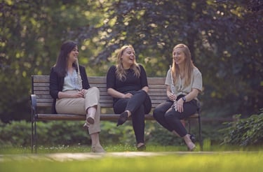 three women sitting on a bench in a park
