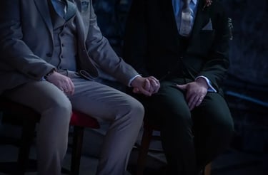 two grooms sitting holding hands