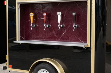 A friendly bartender serving drinks from a mobile tap trailer at a lively outdoor event.