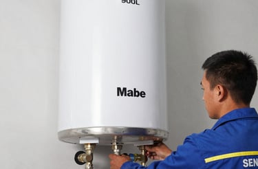 Technician repairing a Mabe gas appliance at a customer's home in Bogotá