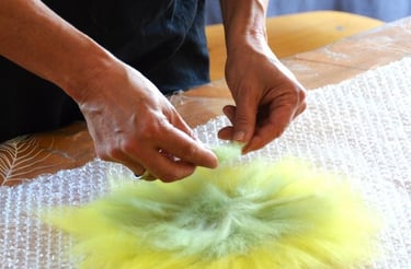 Gros plan sur mes mains disposant la laine pour être feutrée